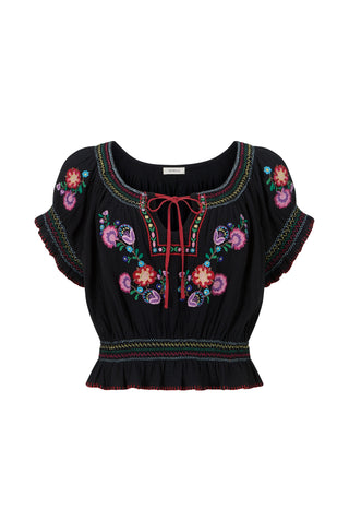a-black-short-sleeve-blouse-with-colorful-floral-embroidery-a-red-tie-neck-bow-and-a-ruffled-hem-shown-against-a-plain-white-background