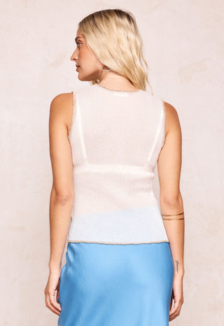 A woman shown from the back wearing a sleeveless ribbed knit top with a color-blocked design in cream and light blue, paired with a light blue satin skirt, against a textured beige background.