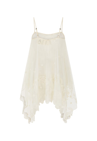 An off-white sheer mesh camisole dress with thin spaghetti straps, a ruffled neckline, and a tiered, asymmetrical hem. The dress features delicate floral embroidery and is displayed against a solid white background.